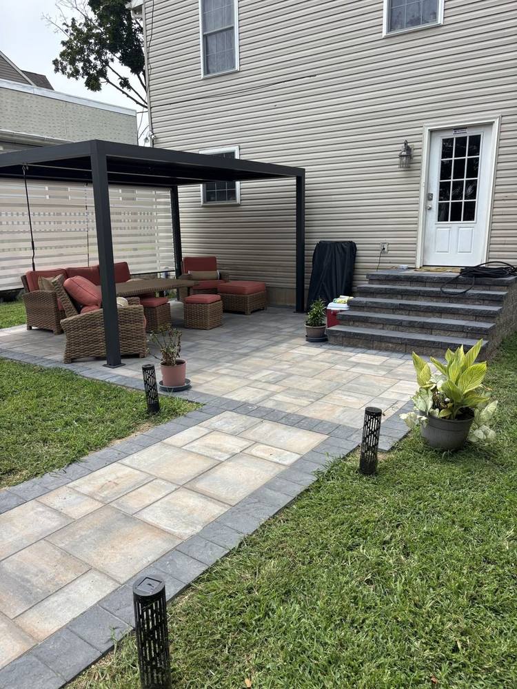 Paver patio under a pergola with block steps to the back door